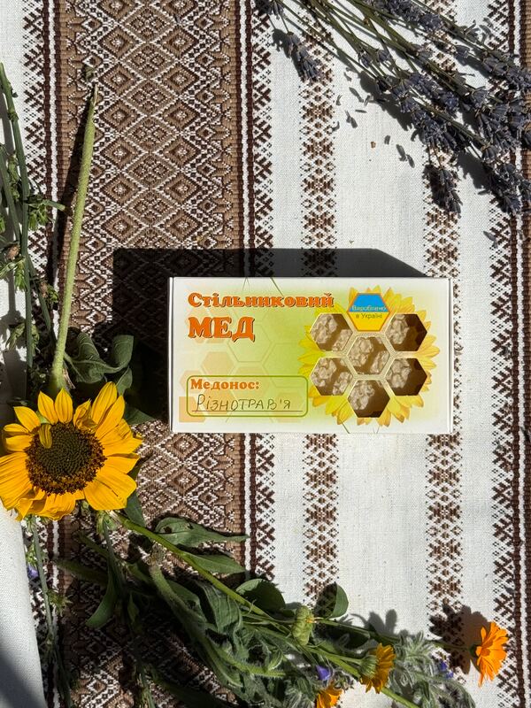 Стільниковий мед у коробці поруч із соняшником